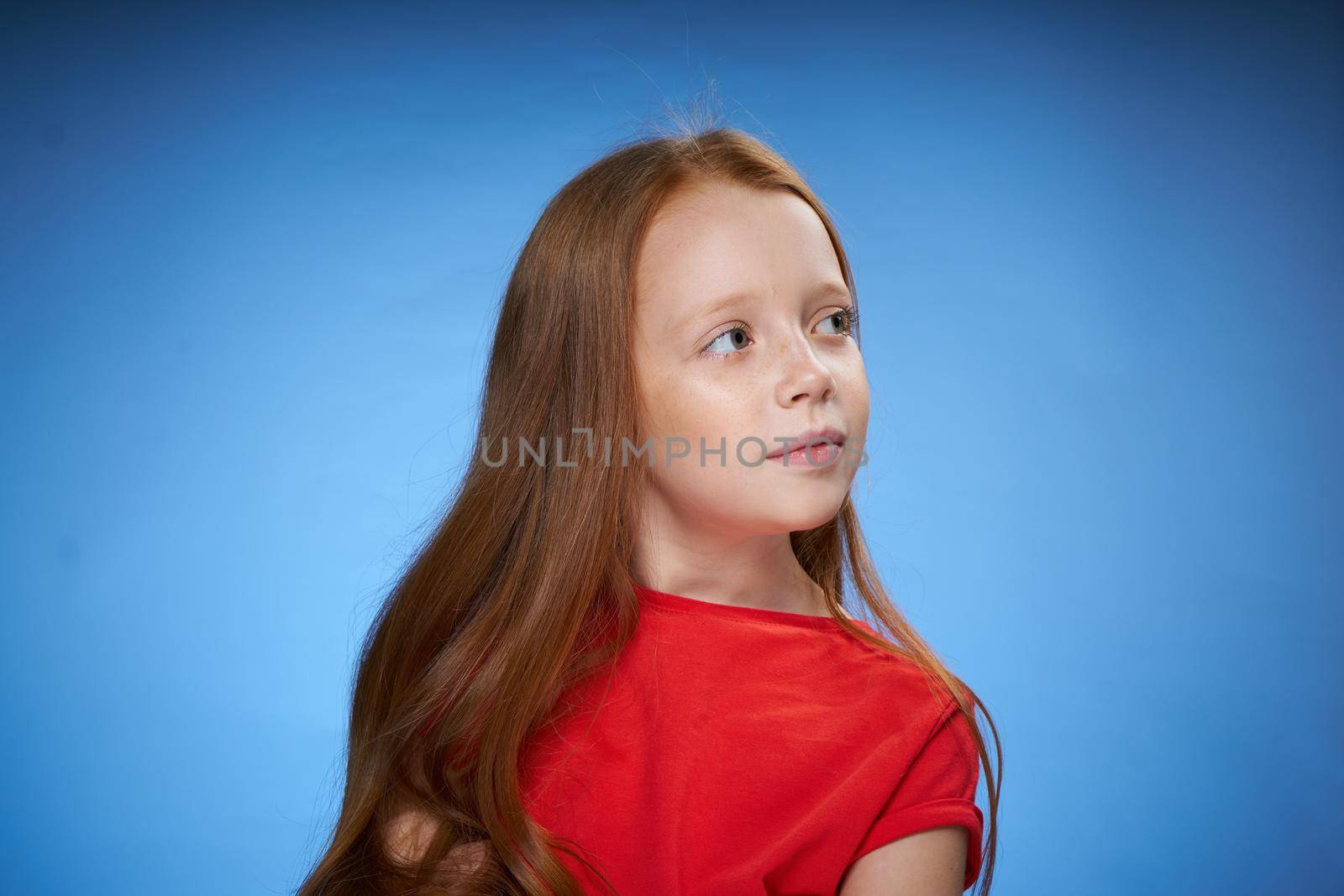 cheerful cute red-haired girl childhood blue background. High quality photo