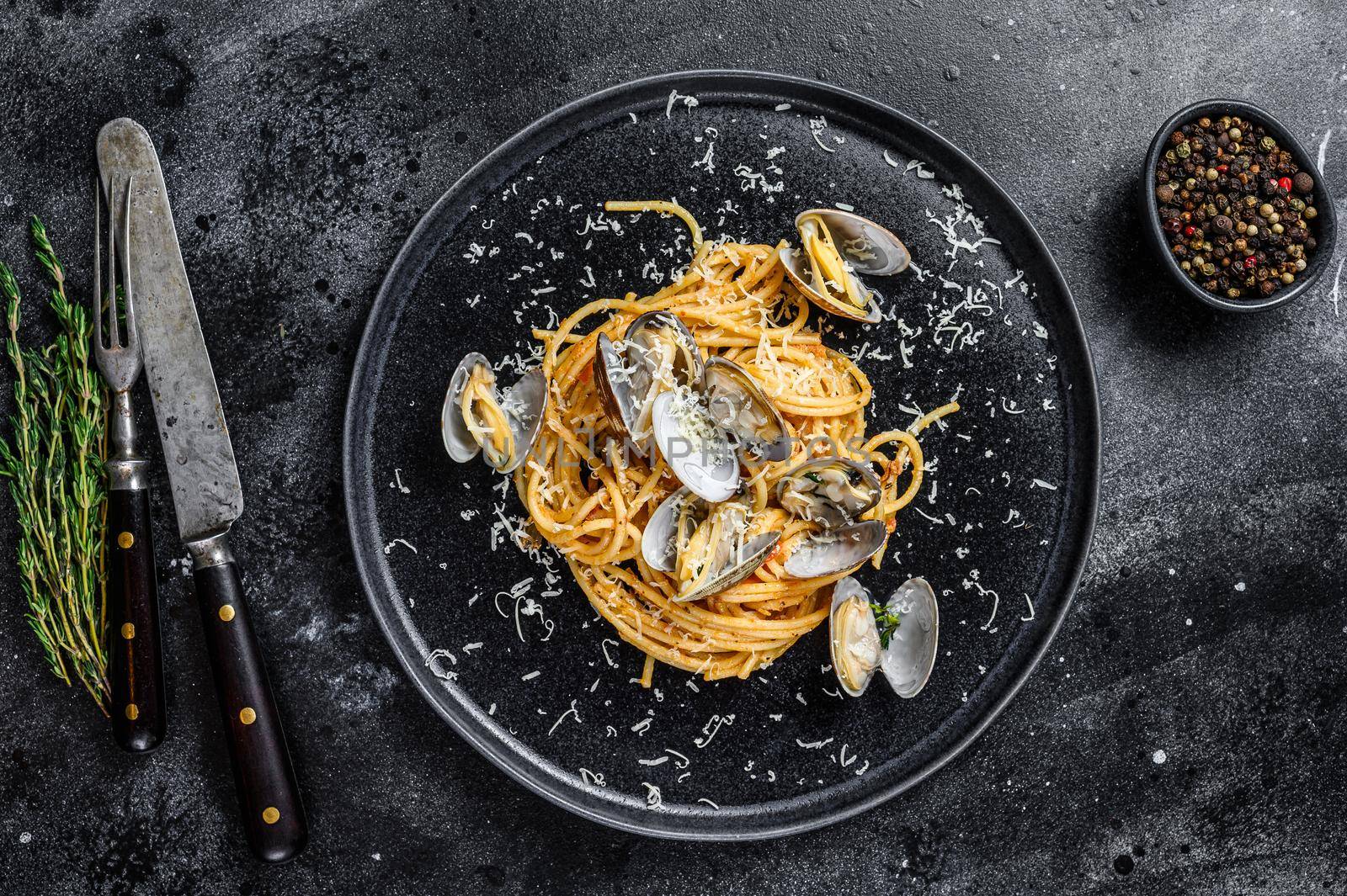 Seafood Spaghetti pasta with Clams vongole in a plate. Black background. Top view.