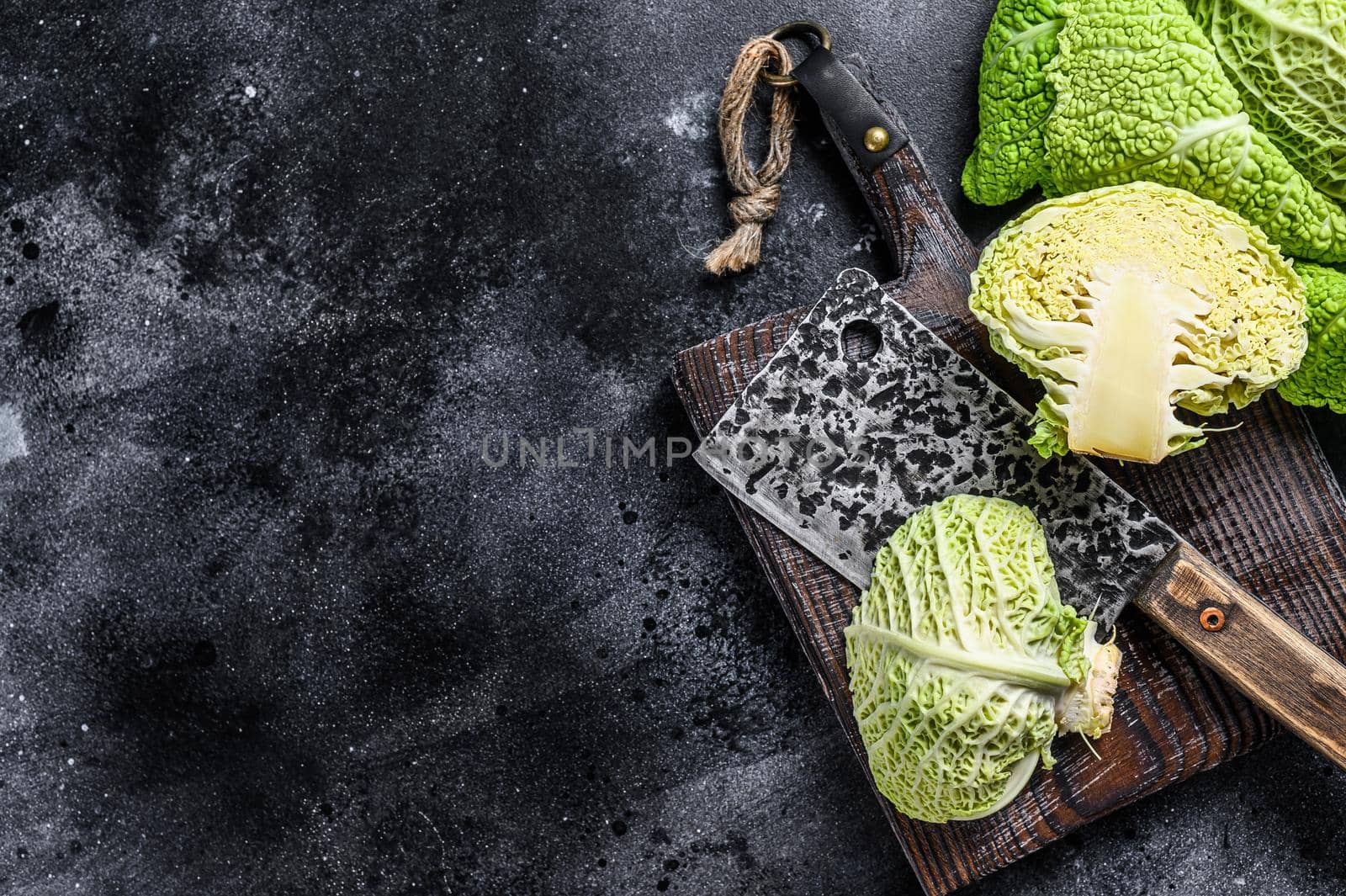 Cut Fresh healthy savoy cabbage on cutting board. Black background. Top view. Copy space.