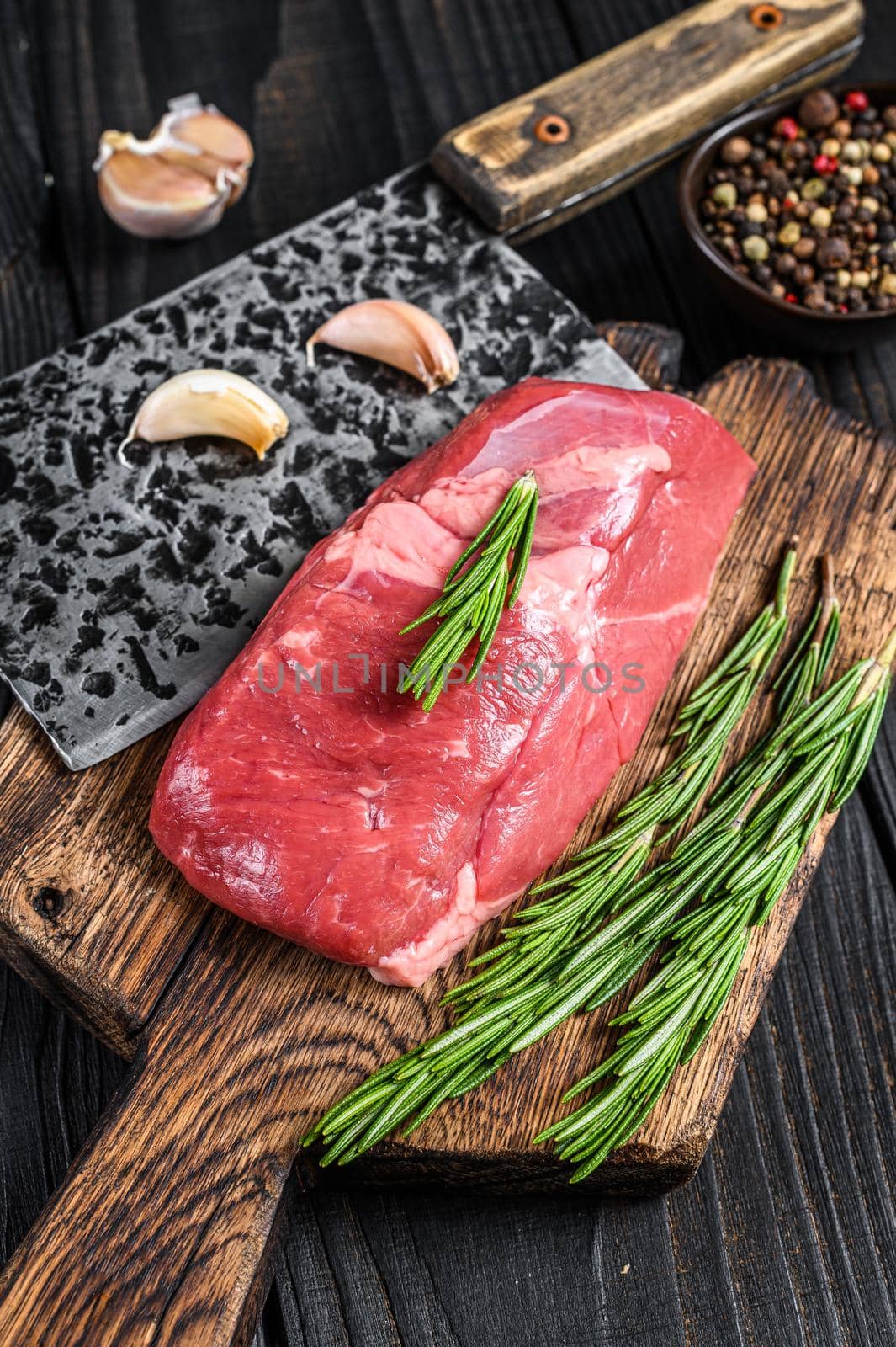 Fresh Raw veal sirloin meat steak on a wooden cutting board. Black wooden background. Top view by Composter