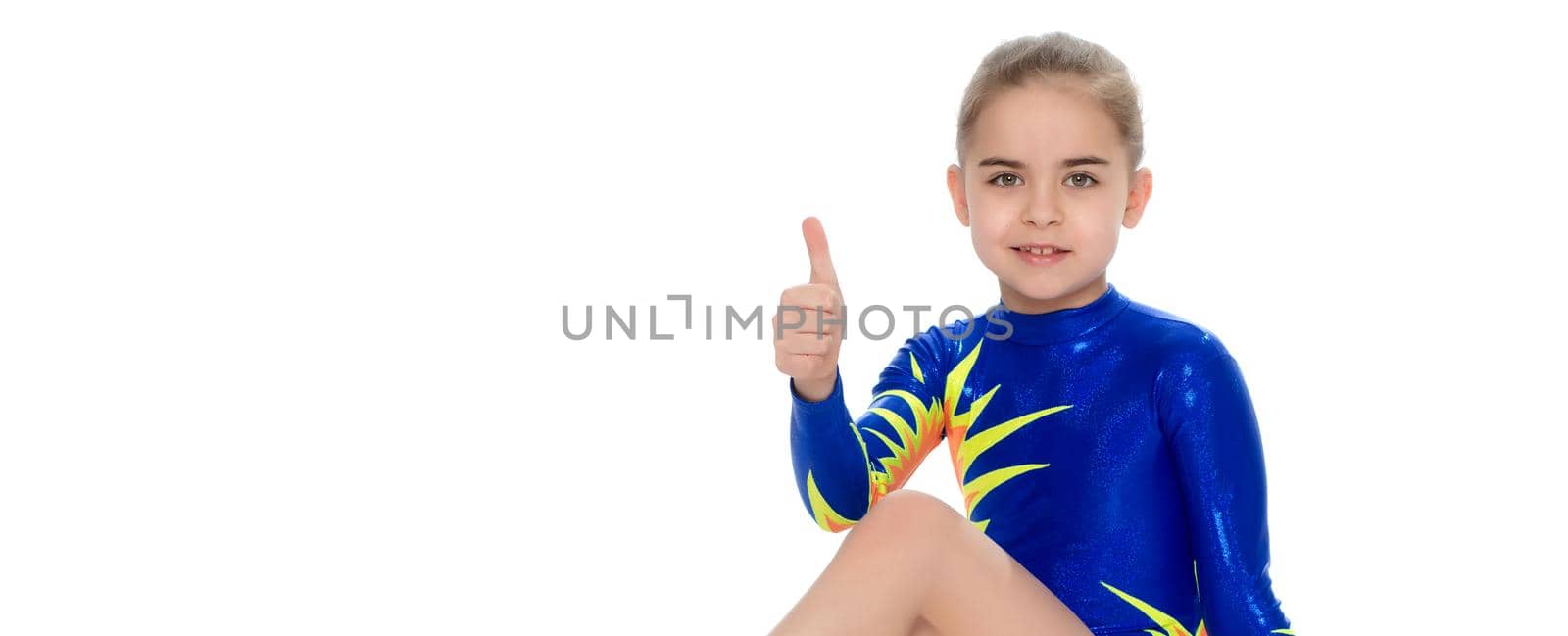 A charming gymnast girl, a younger school age, in a beautiful blue swimsuit, performs an exercise on the floor.She looks directly into the camera.Isolated on white background.