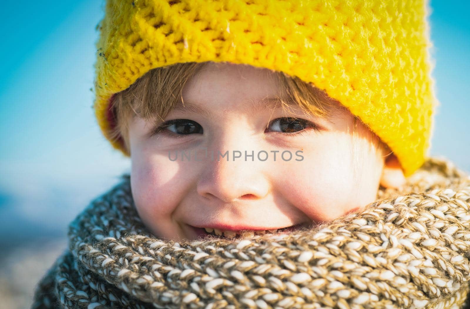 Close up face portrait of boy child in warm winter hat having fun