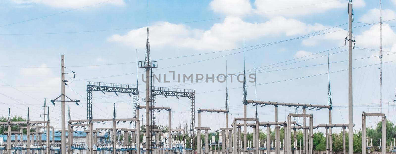 Electric substation of high-voltage power transmission lines electric towers against the background of blue sky.