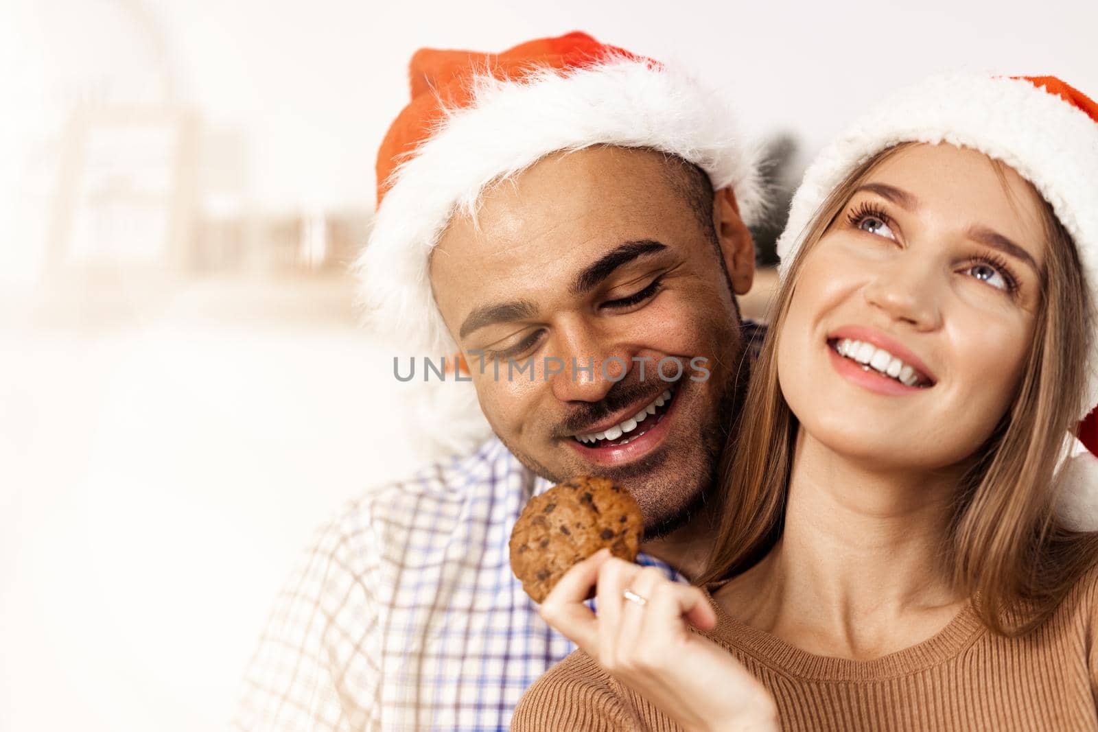 Cheerful attractive happy couple in Santa hats, close up portrait