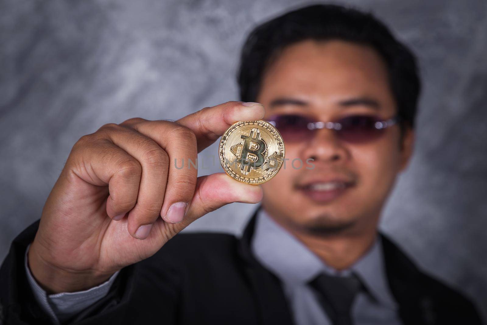 man holding golden bitcoin in hand by geargodz