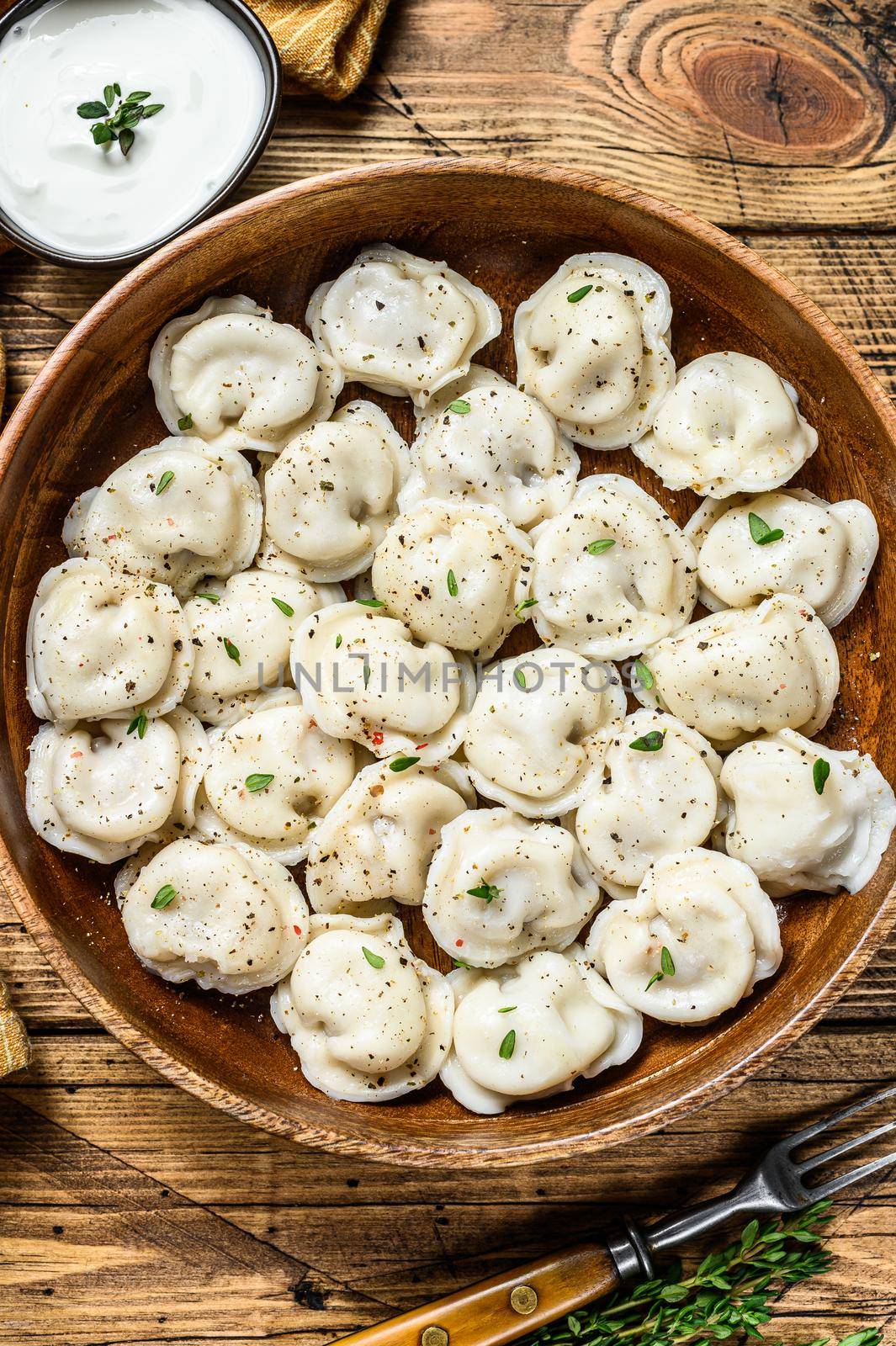 Homemade Russian Dumplings Pelmeni with beef and pork meat in a wooden bowl. wooden background. top view.
