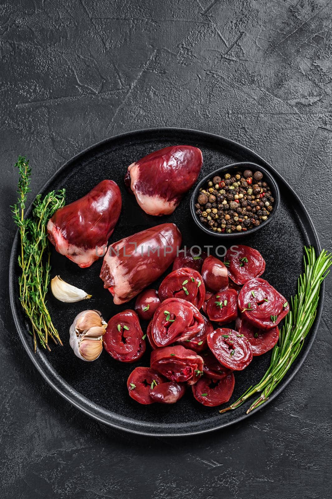 Sliced Raw turkey hearts ready for cooking. Black background. Top view. Copy space by Composter