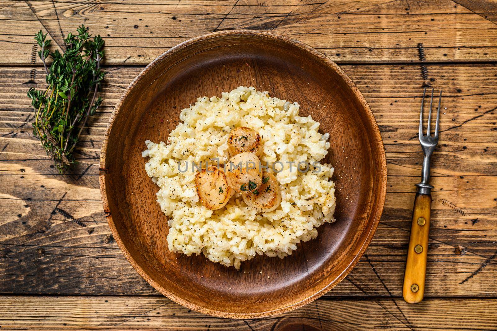 Italian Risotto with Scallops in a pan. wooden background. Top view.