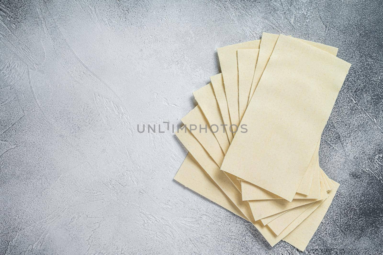 Raw lasagna sheets stack on a kitchen table. White background. Top view. Copy space by Composter