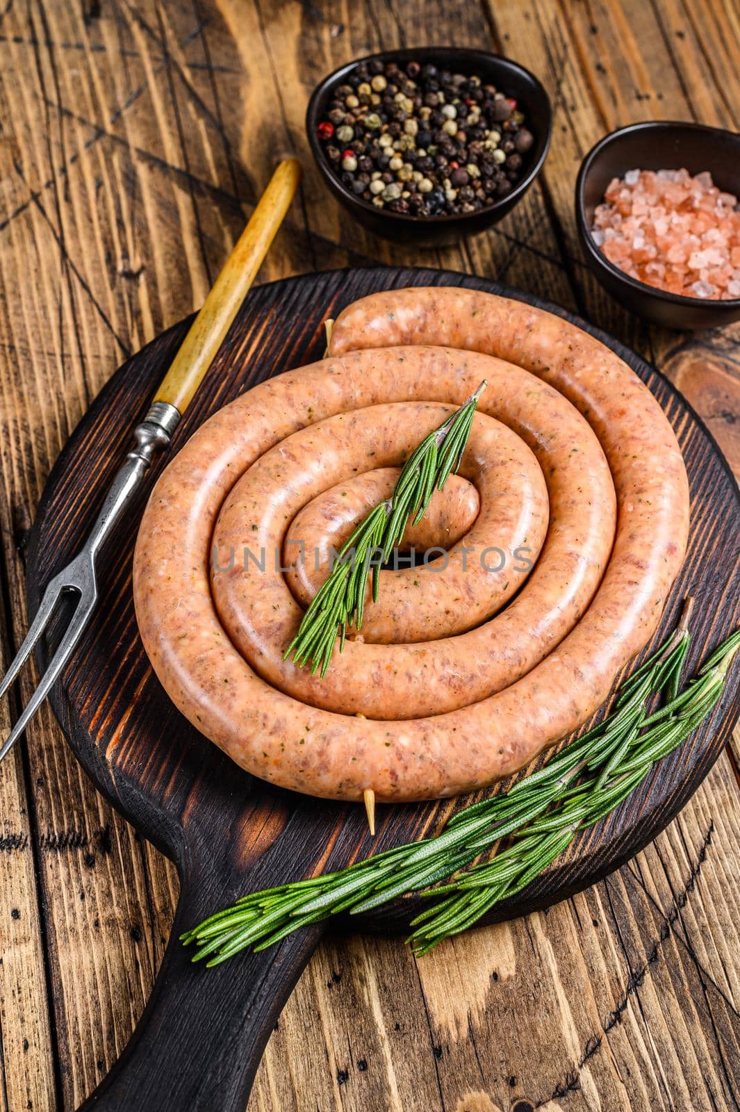 Raw spiral barbecue sausage from pork and beef ground meat. Wooden background. Top view.