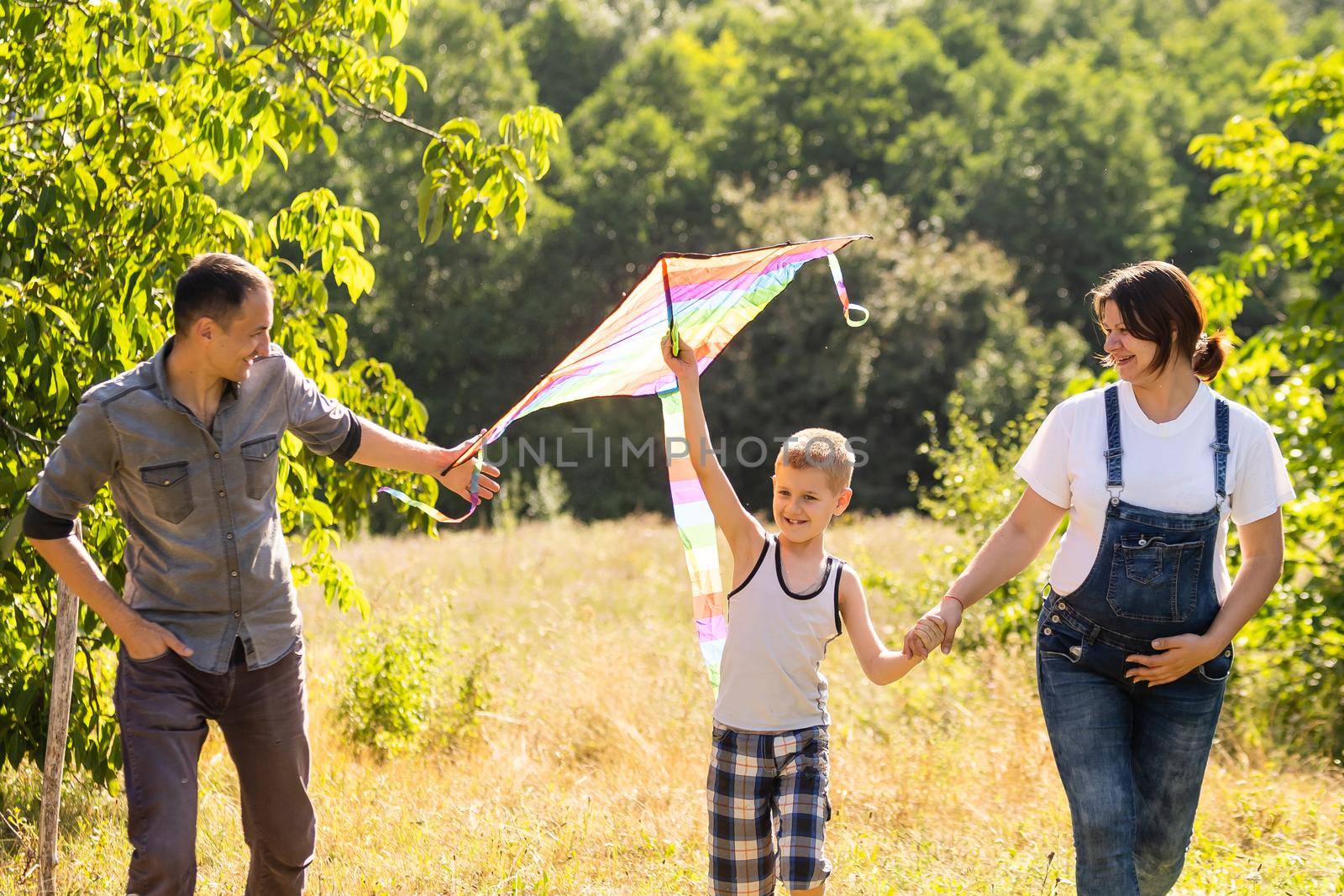 Young parents go with the son on the wheat field . The little son is happy when he is played. by Andelov13