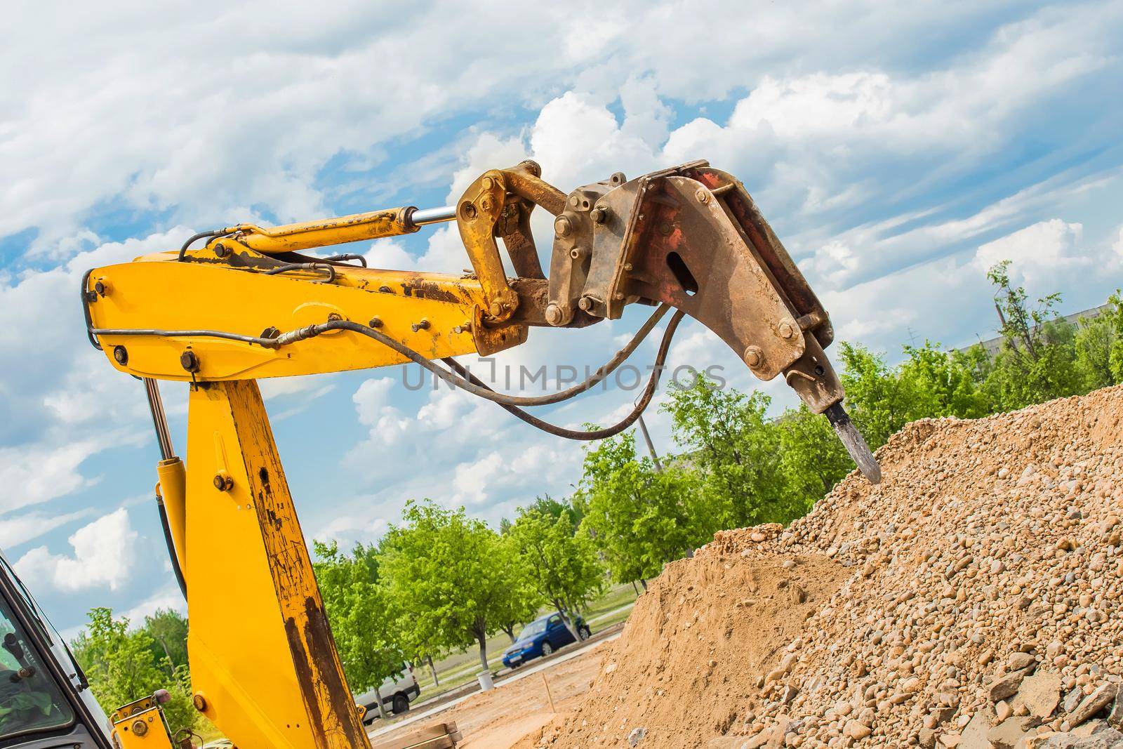 Mechanical equipment industrial vibratory hammer for drilling stones and concrete structures in the background of a construction site.