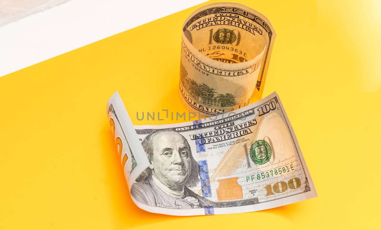 Single Hundred Dollar Bill Curled on yellow. High quality photo