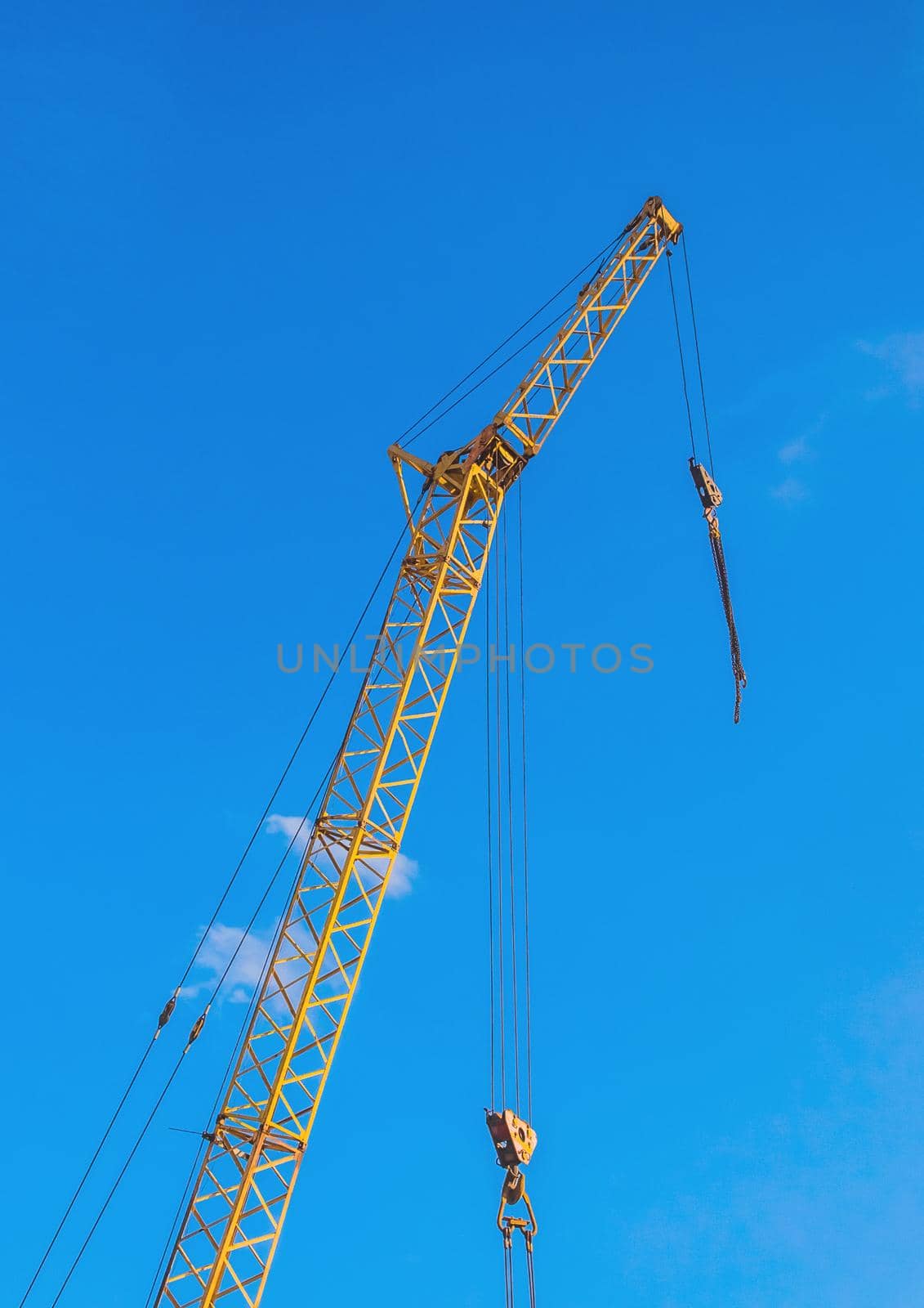 Hoisting machine industrial crane equipment against blue sky at construction site by AYDO8