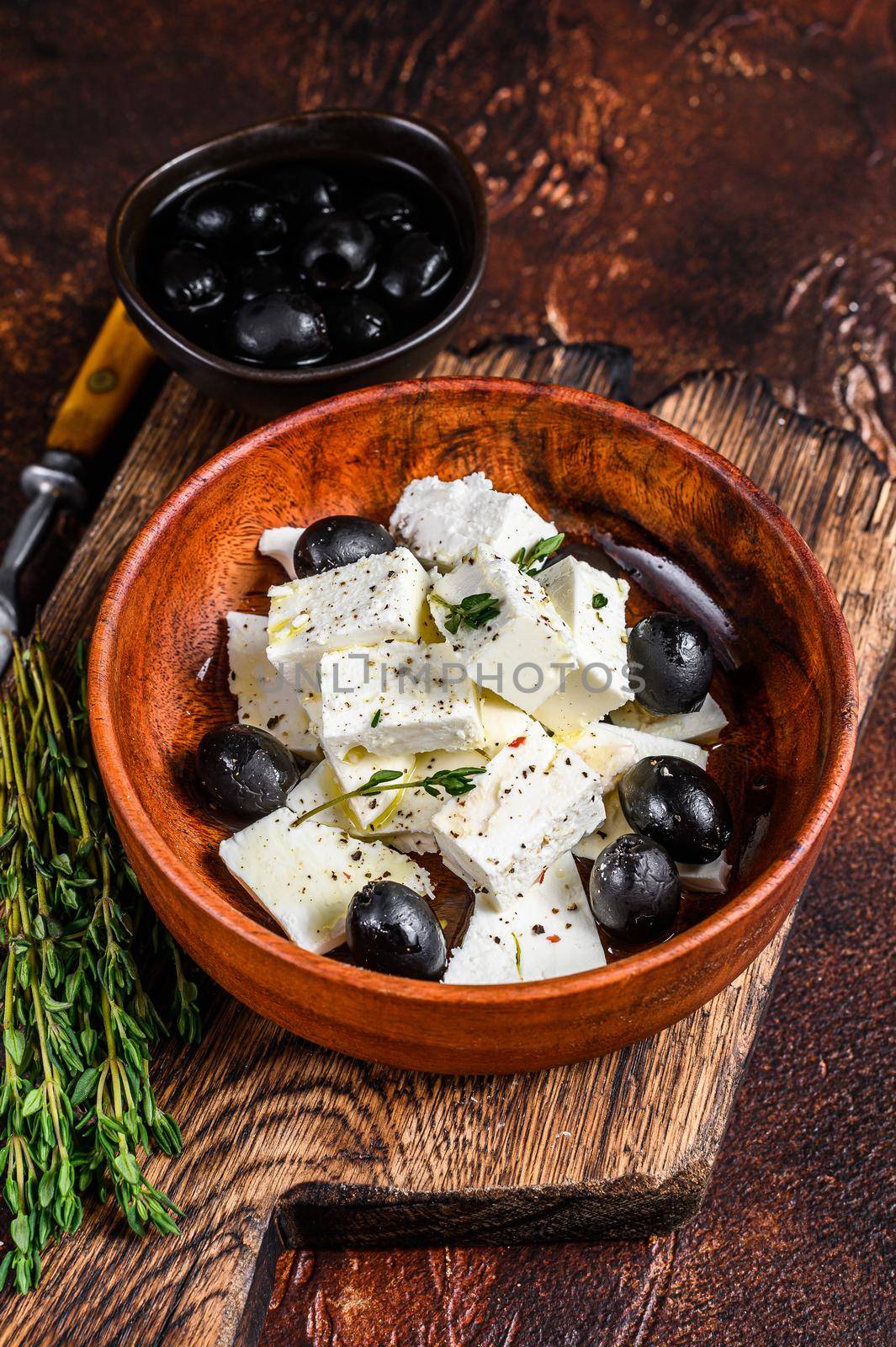 Salad with fresh feta cheese, thyme and olives. Dark background. Top view.
