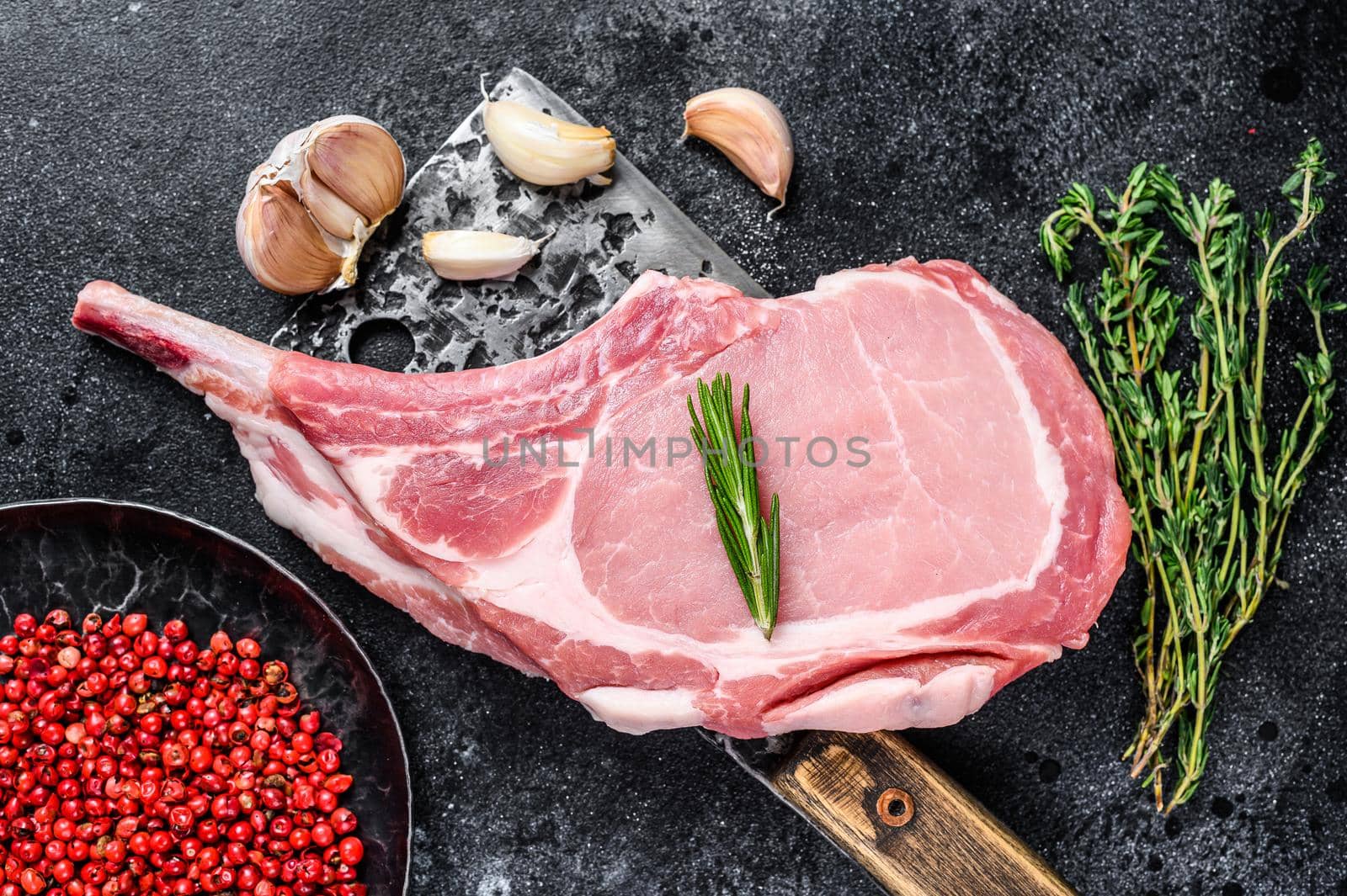 Raw tomahawk pork chop meat steak on a meat cleaver. Black background. Top view by Composter