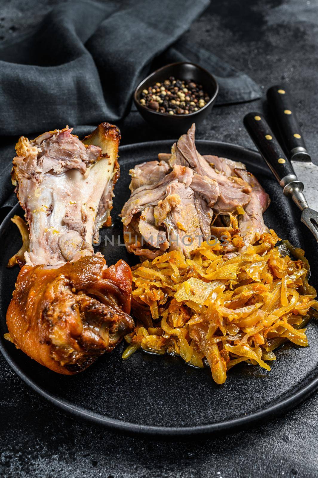 Pork leg eisbein with braised cabbage. Black background. Top view.