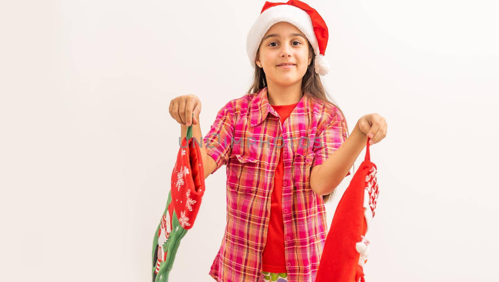 Cute smiling toddler girl in a red dress checking her Christmas stocking.