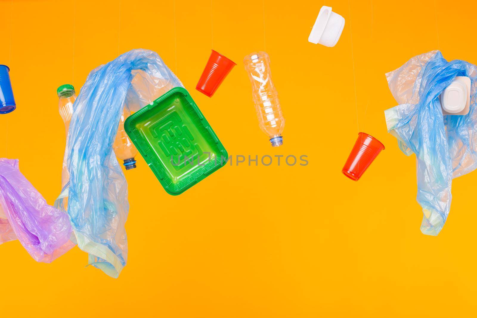 Environmental pollution, plastic recycling problem and ecology problem concept - different plastic garbage on yellow background. by Satura86