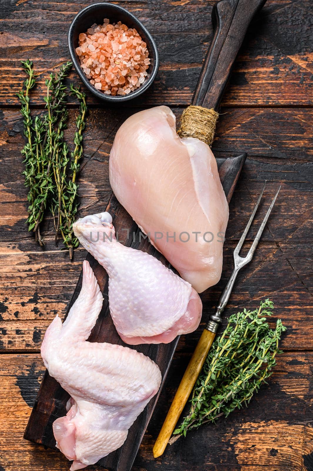 Raw chicken portions for cooking and barbecuing with skinless breasts, drumstick and wings. Dark wooden background. Top view by Composter