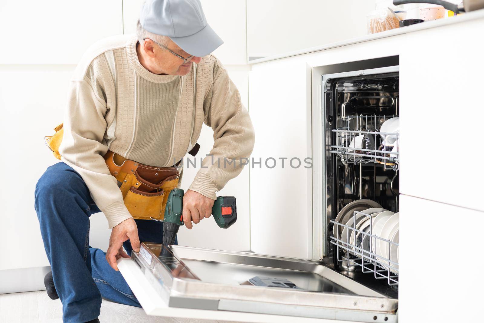 Technician or plumber repairing the dishwasher in a household by Andelov13