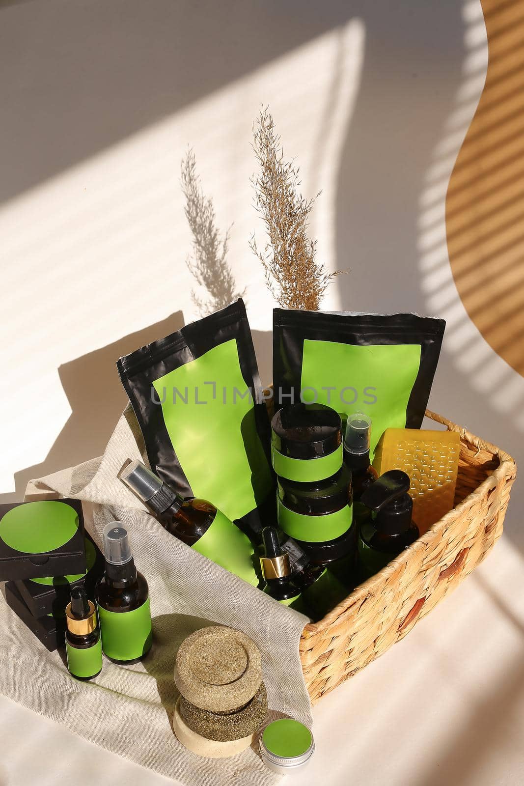Cosmetic bottles, jars and doy packs in wicker basket with green space for brand. Concept of organic cosmetics and cluelty free kosher products in online shop.