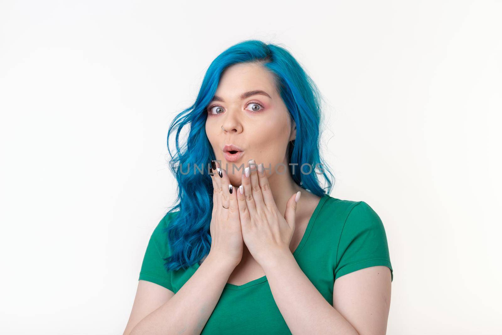 Young beautiful woman with blue hair with facial expression of surprise standing over white background