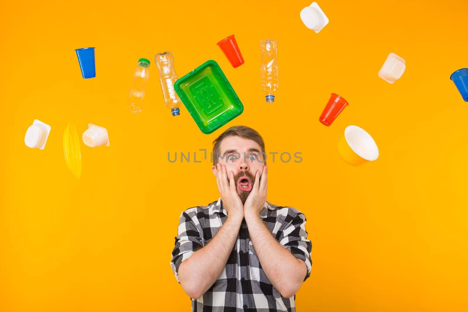 World Environment Day, plastic recycling problem and environmental disaster concept - Terrified man on yellow background with trash.