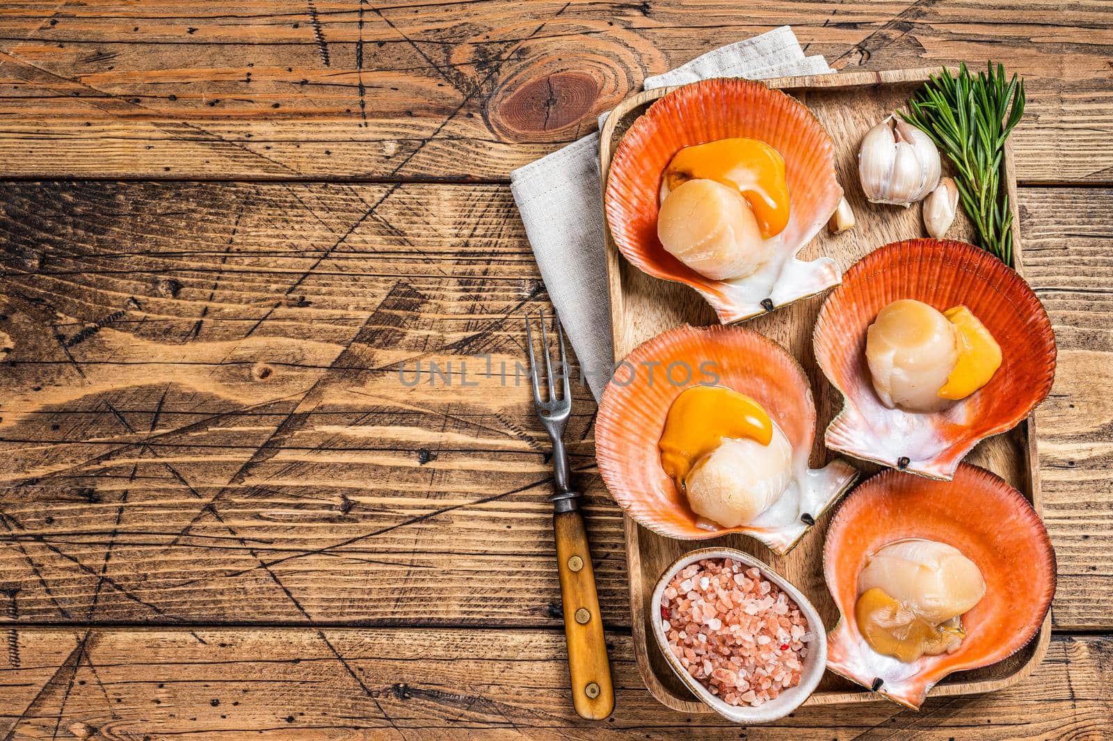 Scallops seafood on a wooden board with salt and herbs. wooden background. Top view. Copy space by Composter