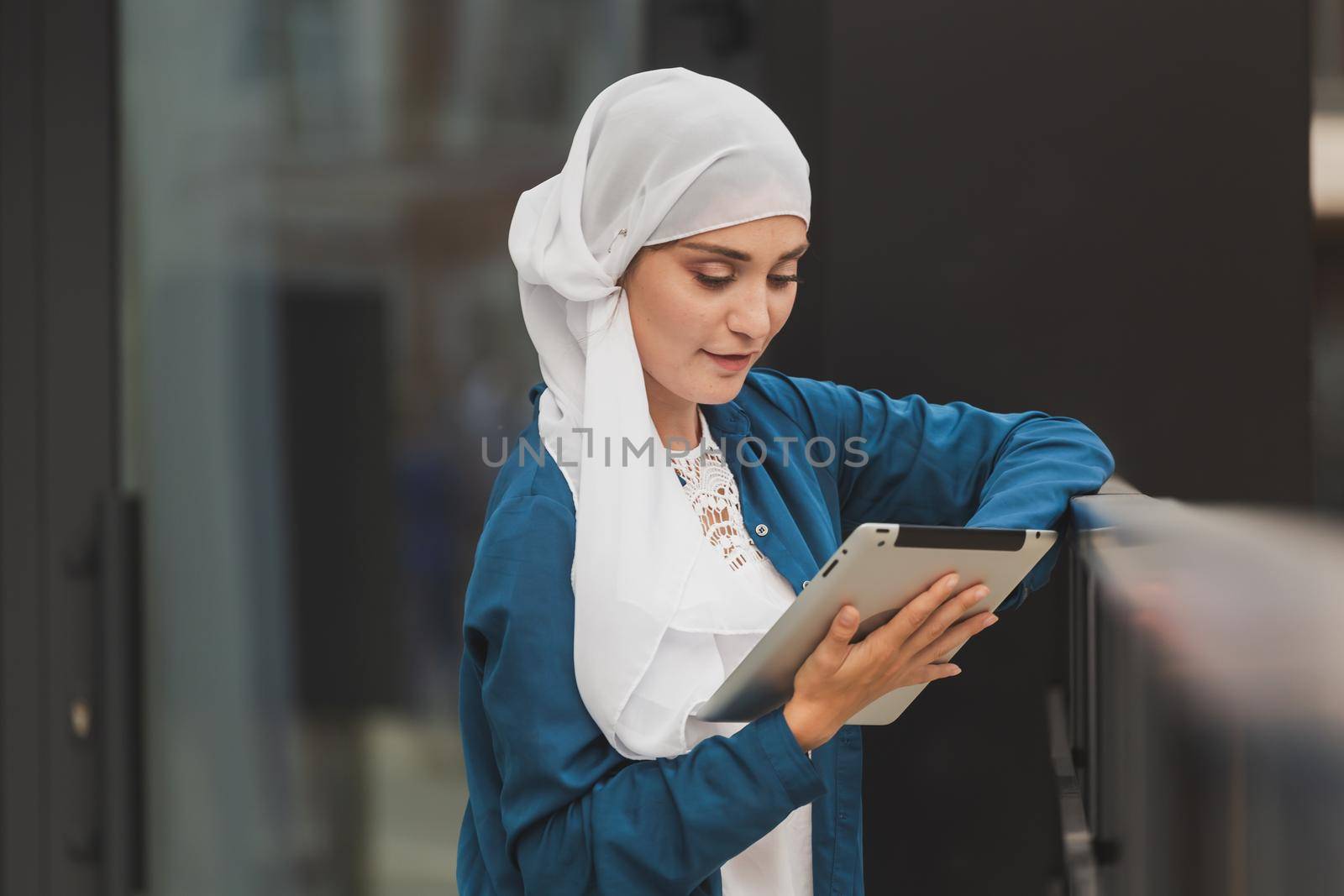 Beautiful Asian businesswomen wearing hijab using her tablet at outdoor.