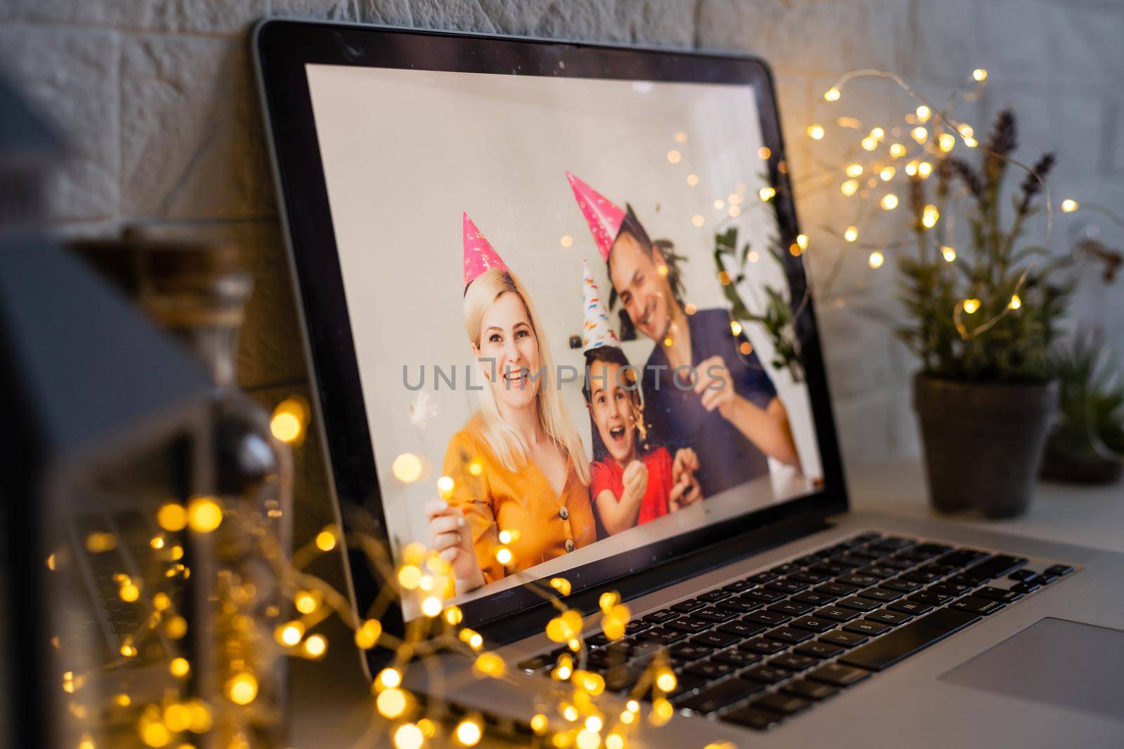 Happy parents hugging cute small kid daughter holding present giving Christmas gift to web camera during virtual family social meeting on video conference call party at home, laptop webcam view. by Andelov13