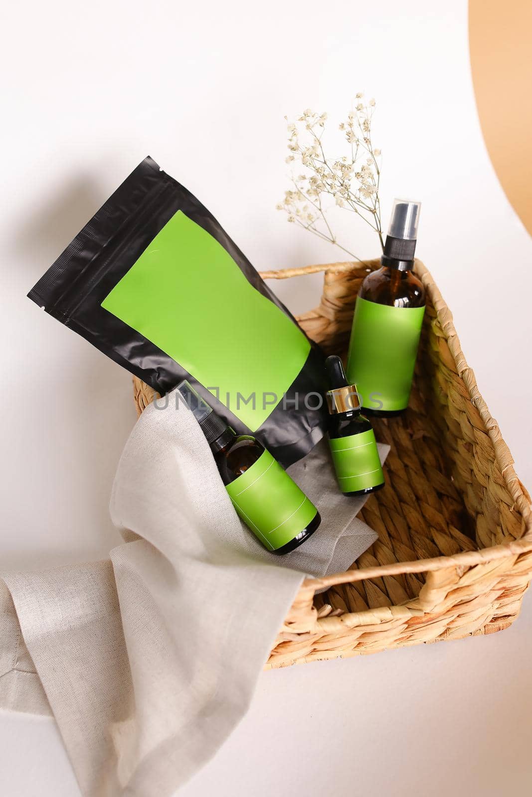 Doy pack and spray bottles with cosmetic products in wicker basket, green space for your brand. by sisterspro