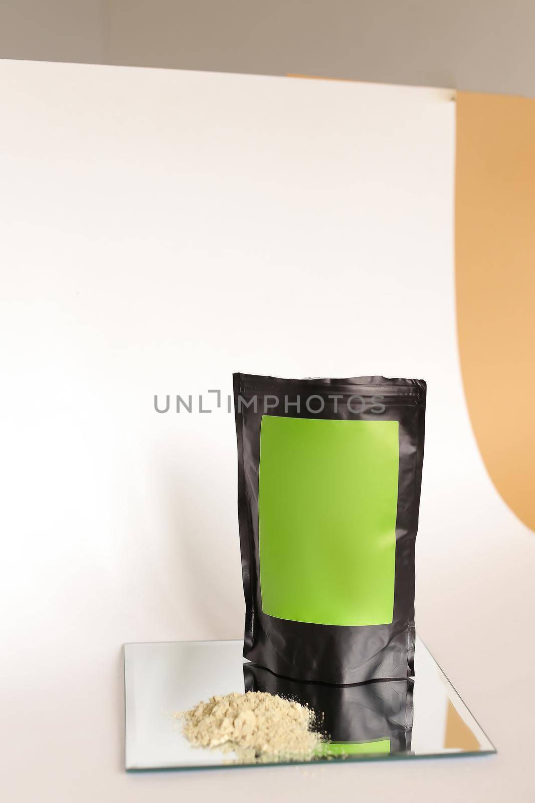 Close up black doy pack with cosmetic product and green space for your brand, powder on glass, white background. Concept of cluelty free, organic, kosher flour and organic cosmetics online shop.