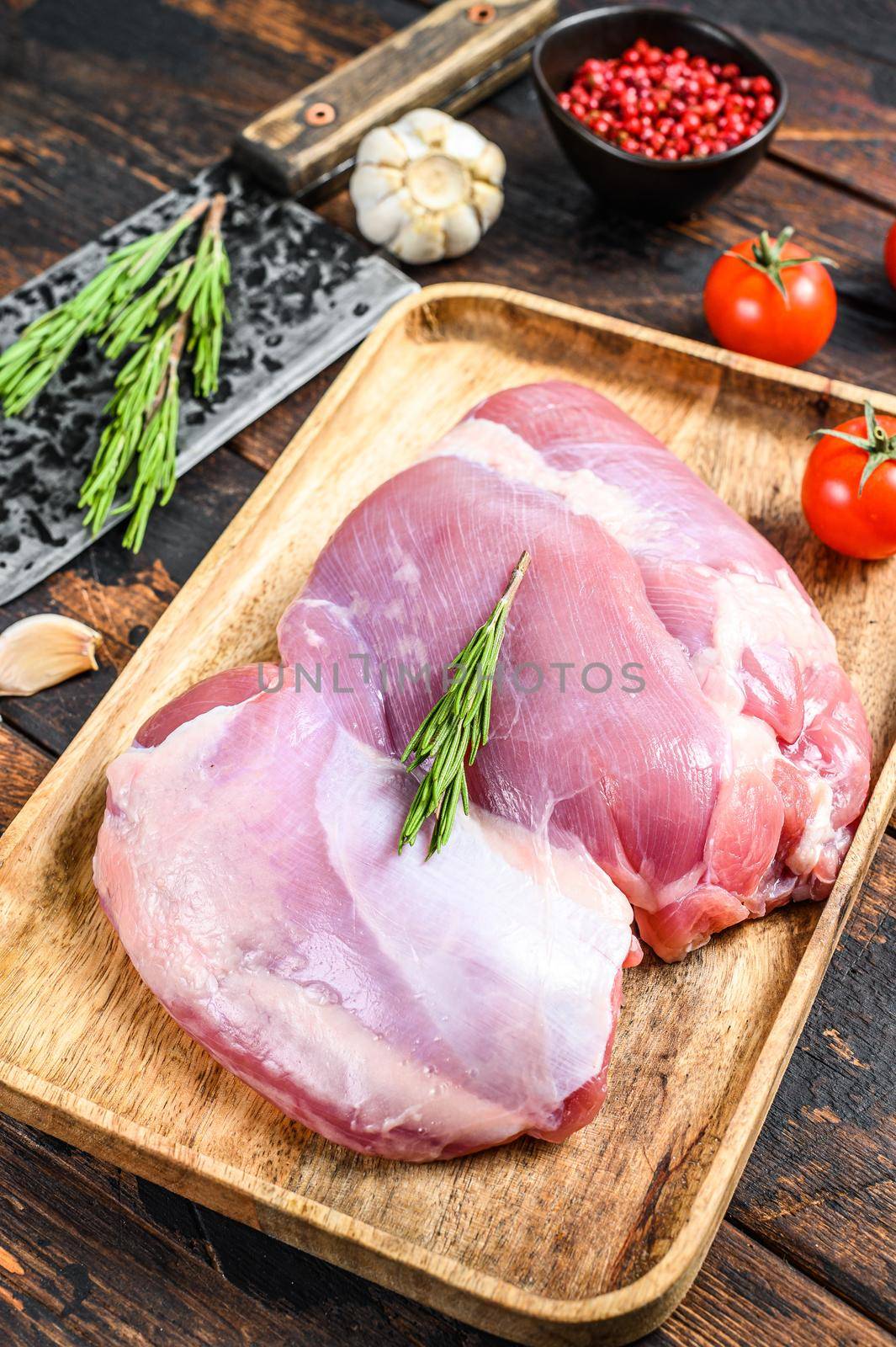 Raw fillet of farm Turkey thigh. Dark wooden background. Top view by Composter