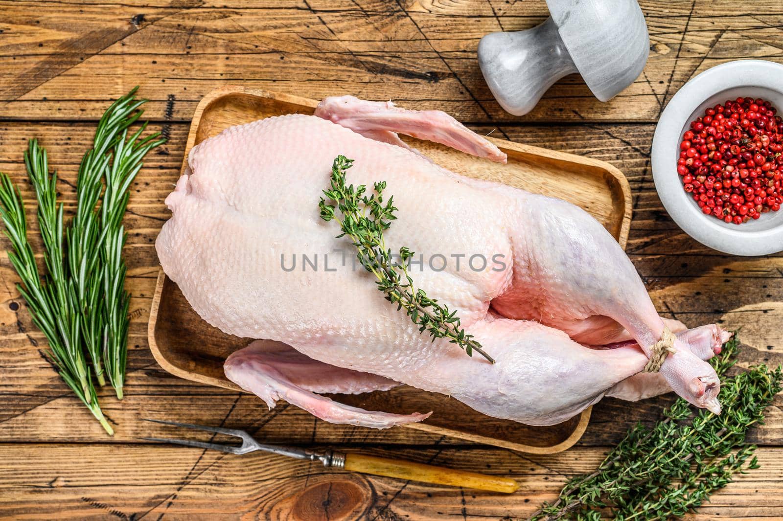 Raw whole farm duck with herbs. wooden background. Top view.