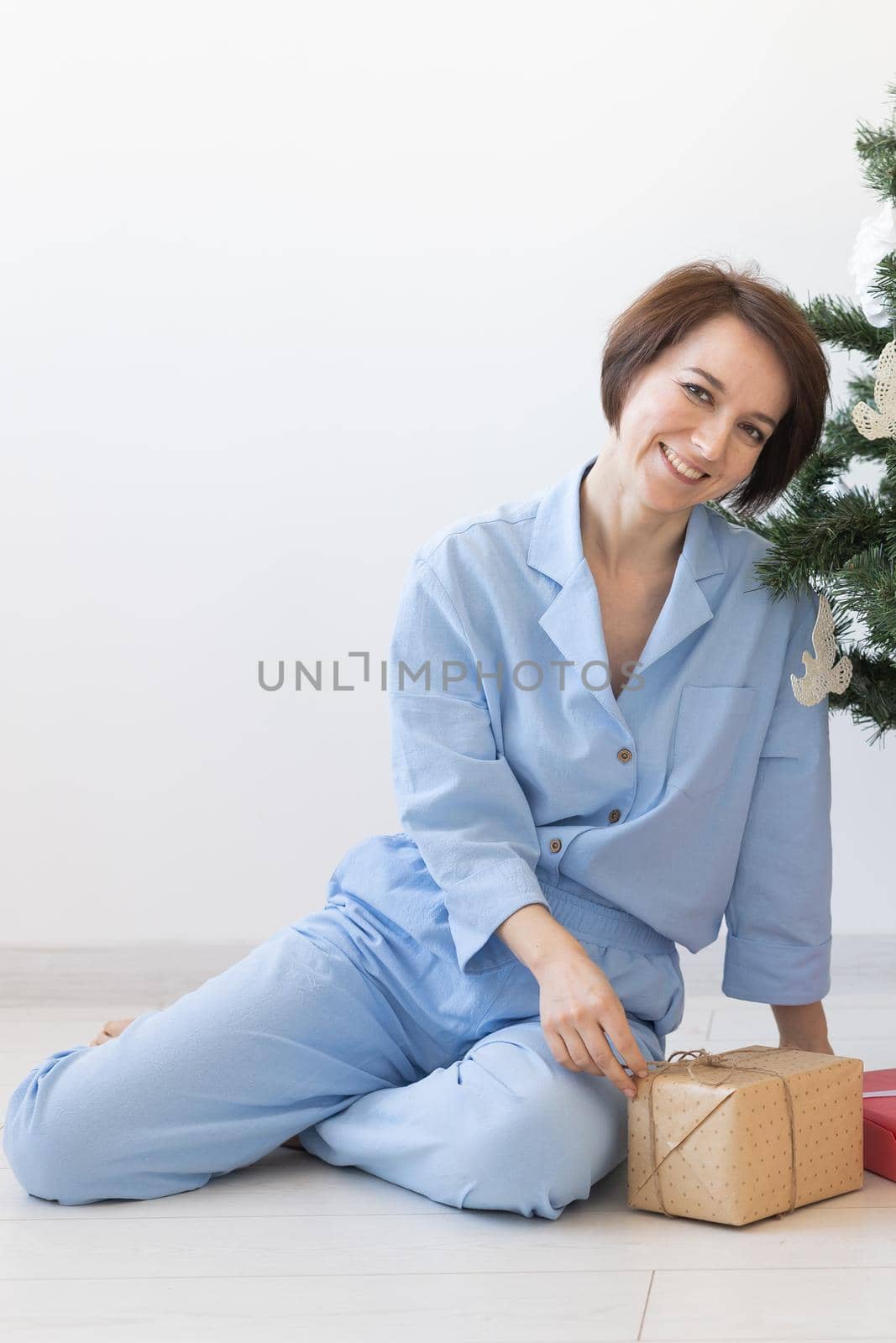 Young woman opens gifts under Christmas tree. Christmas and new year concept.