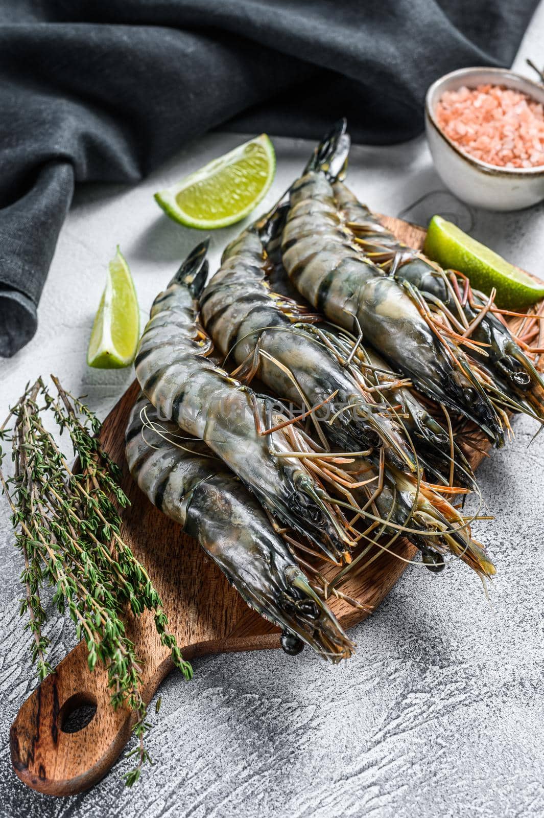 Fresh tiger shrimps, prawns with spices and herbs on a cutting board. Gray background. Top view by Composter