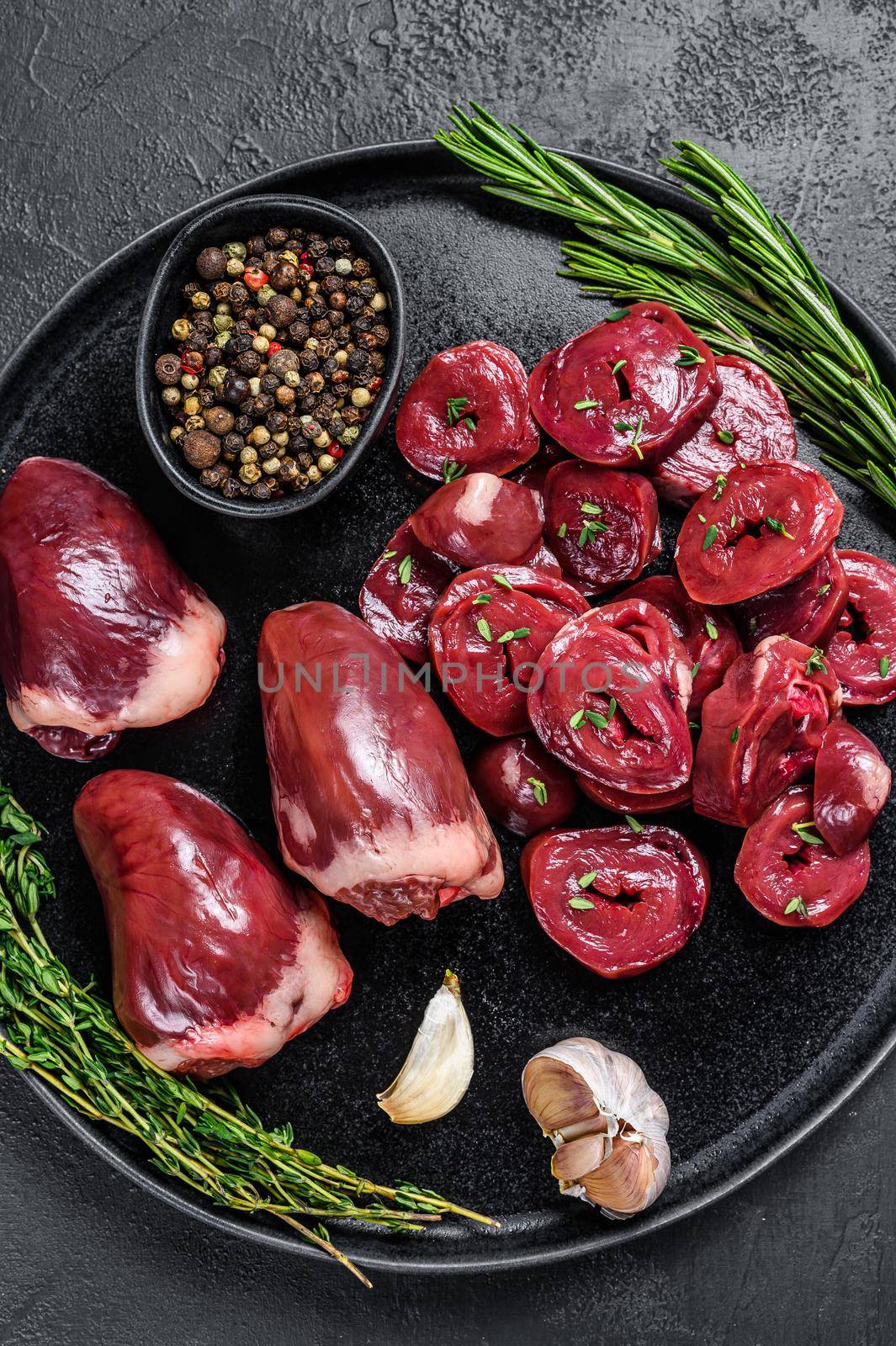 Sliced Raw turkey hearts ready for cooking. Black background. Top view by Composter