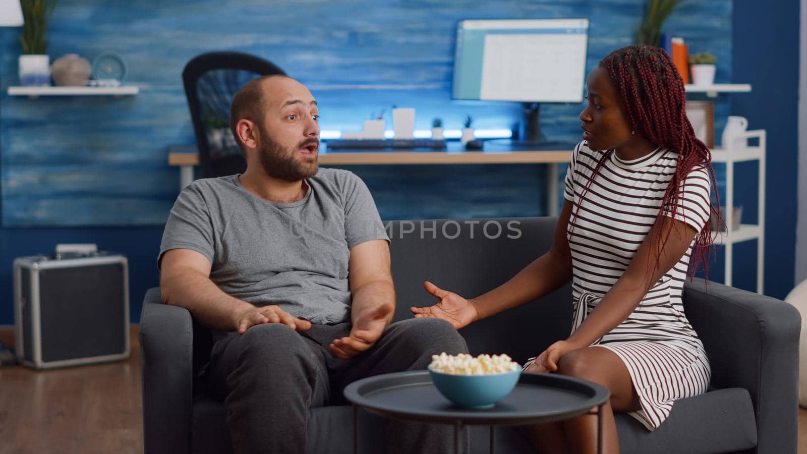 Married interracial people with marriage problems yelling at each other in living room. Mixed race young couple fighting at home while sitting on sofa, having argument and being irritated