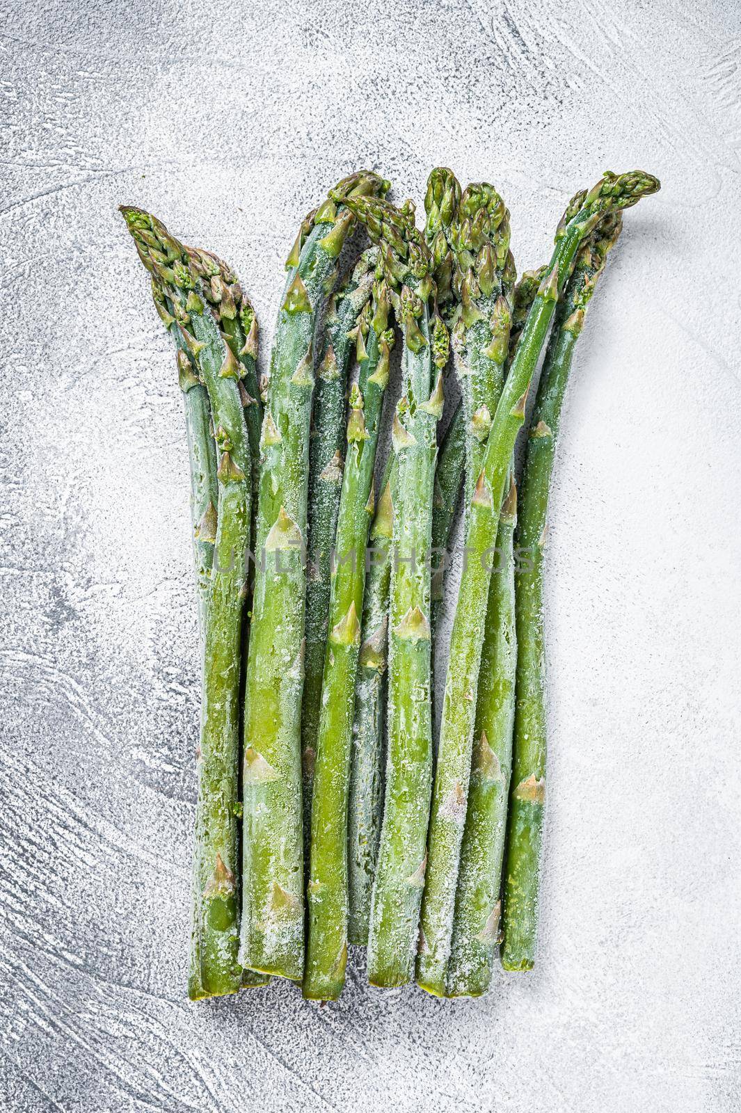 Frozen cold asparagus on a old kitchen table. White background. Top view.