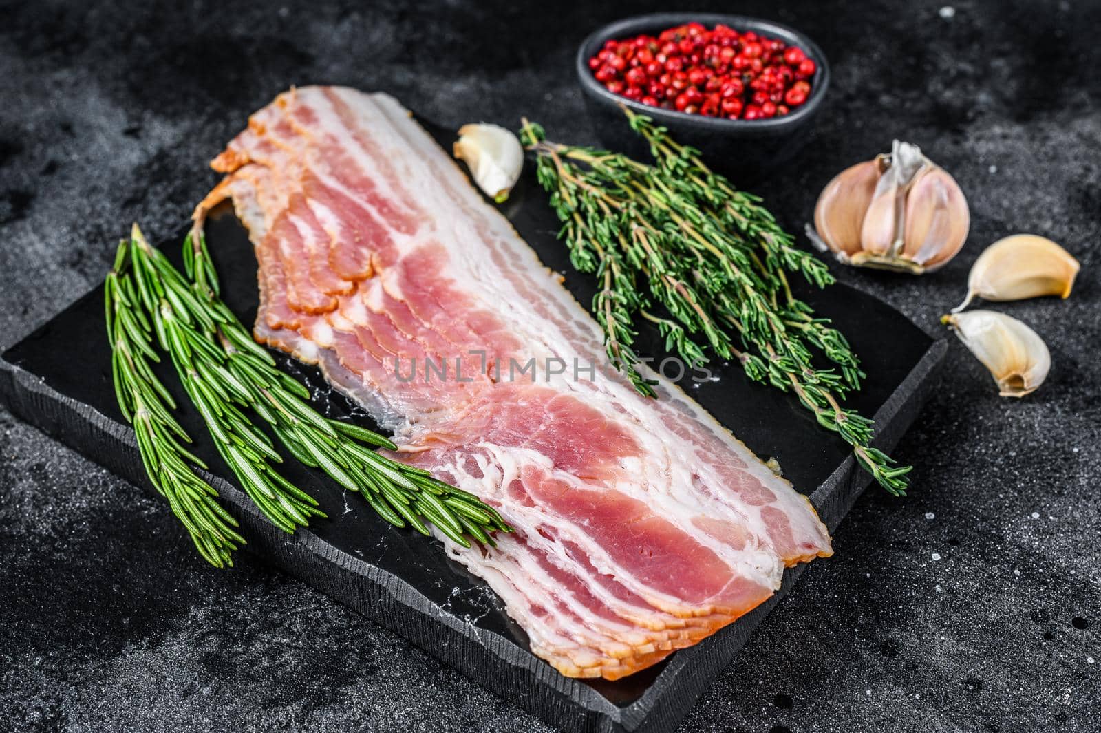 Raw sliced pork bacon ready for cooking. Black background. Top view by Composter