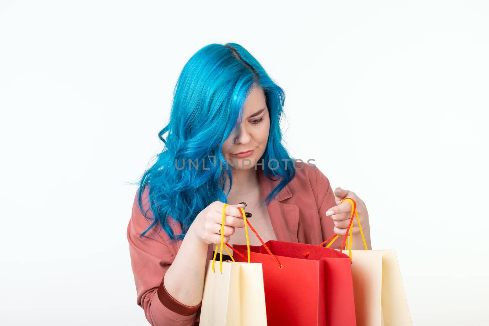 Sale, shopaholic and consumer concept - beautiful girl with blue hair standing with shopping bags on white background.