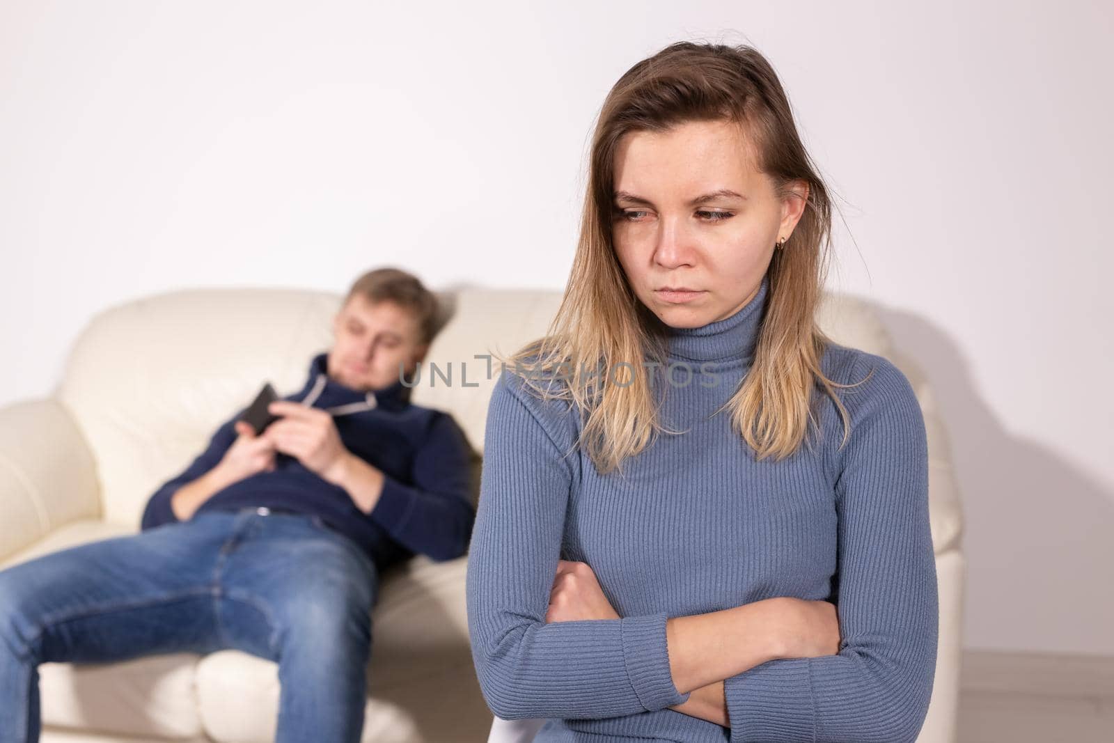 People, domestic violence and abuse concept - Woman with crossed arms and man on the white sofa by Satura86