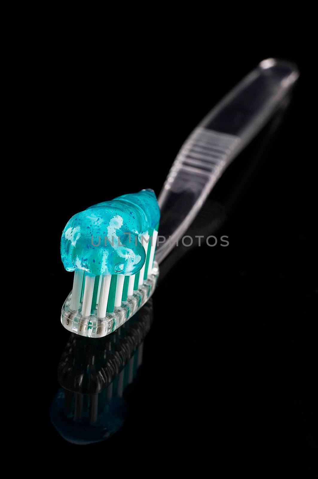 toothbrush and paste over black reflective background