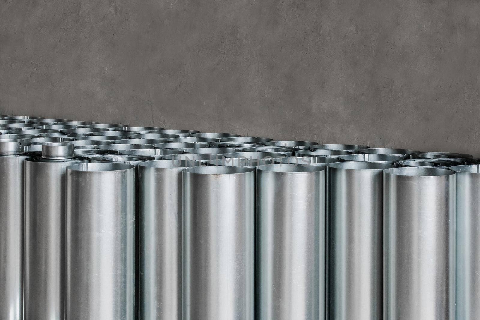 Pile of round metal pipes at a construction site. Storage steel tube industrial materials on warehouse.