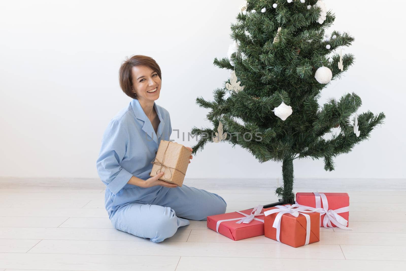 Young woman opens gifts under Christmas tree. Christmas and new year concept.