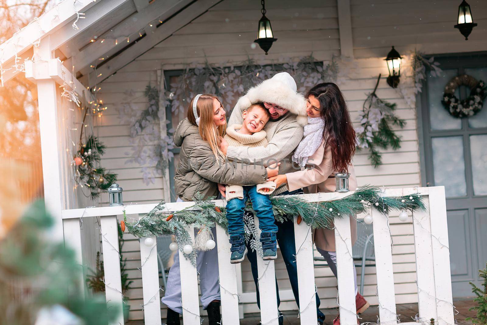 Happy family on the porch of the Christmas decorated house outdoor by Len44ik
