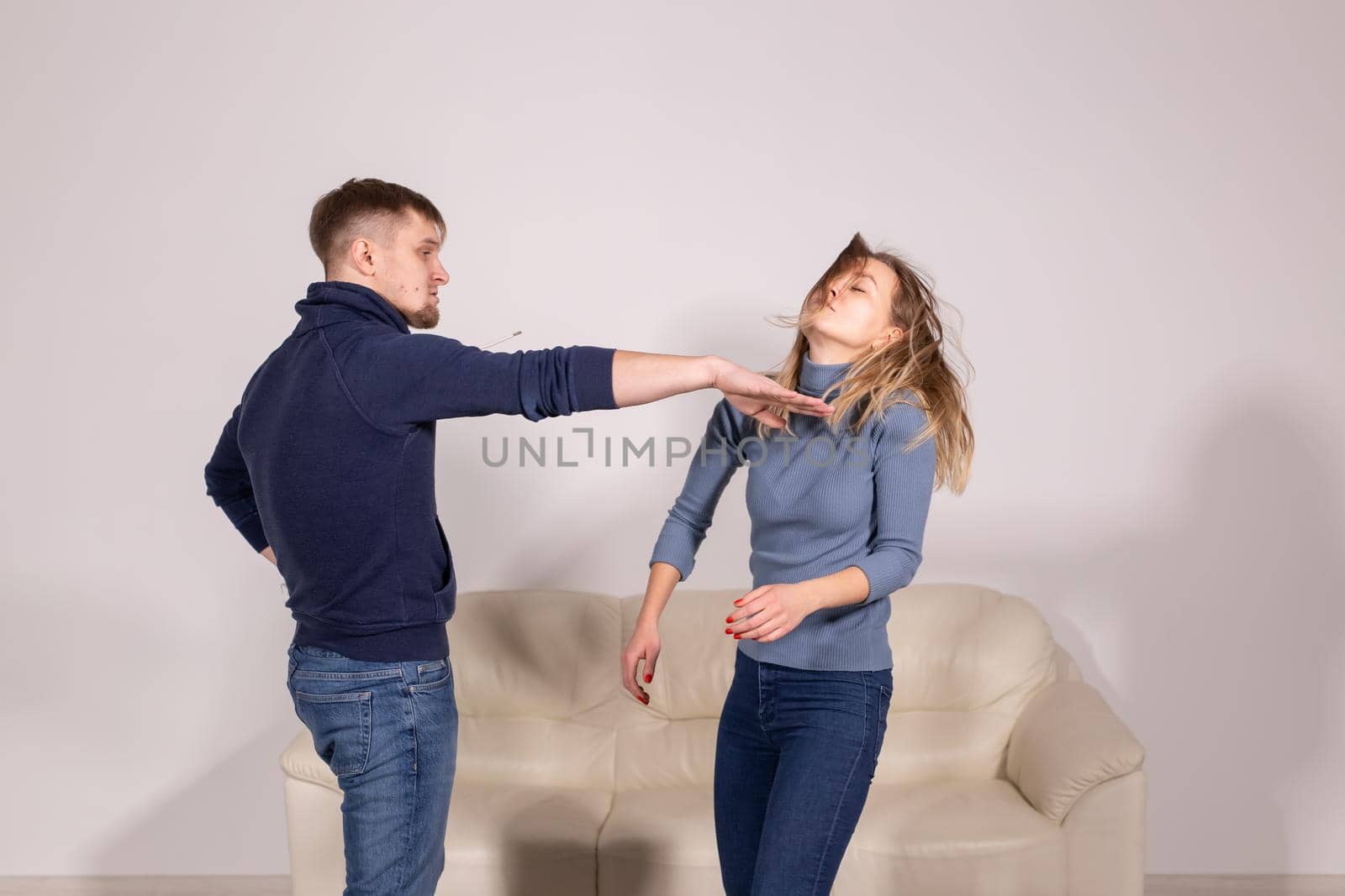 people, violence and abuse concept - angry man hitting woman in her face on sofa.