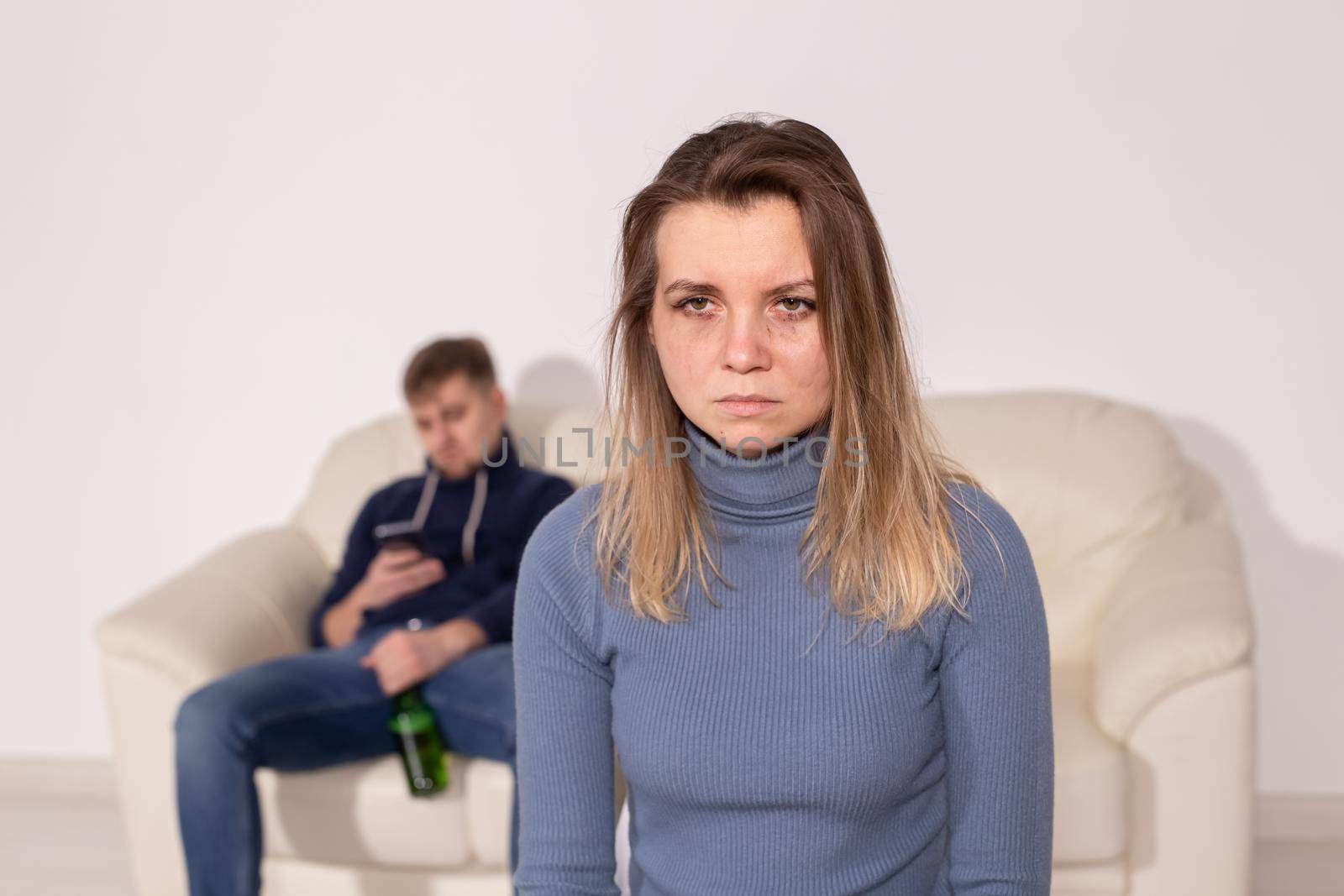 Alcoholism, abuse and domestic violence concept - sad woman with her drunk husband.