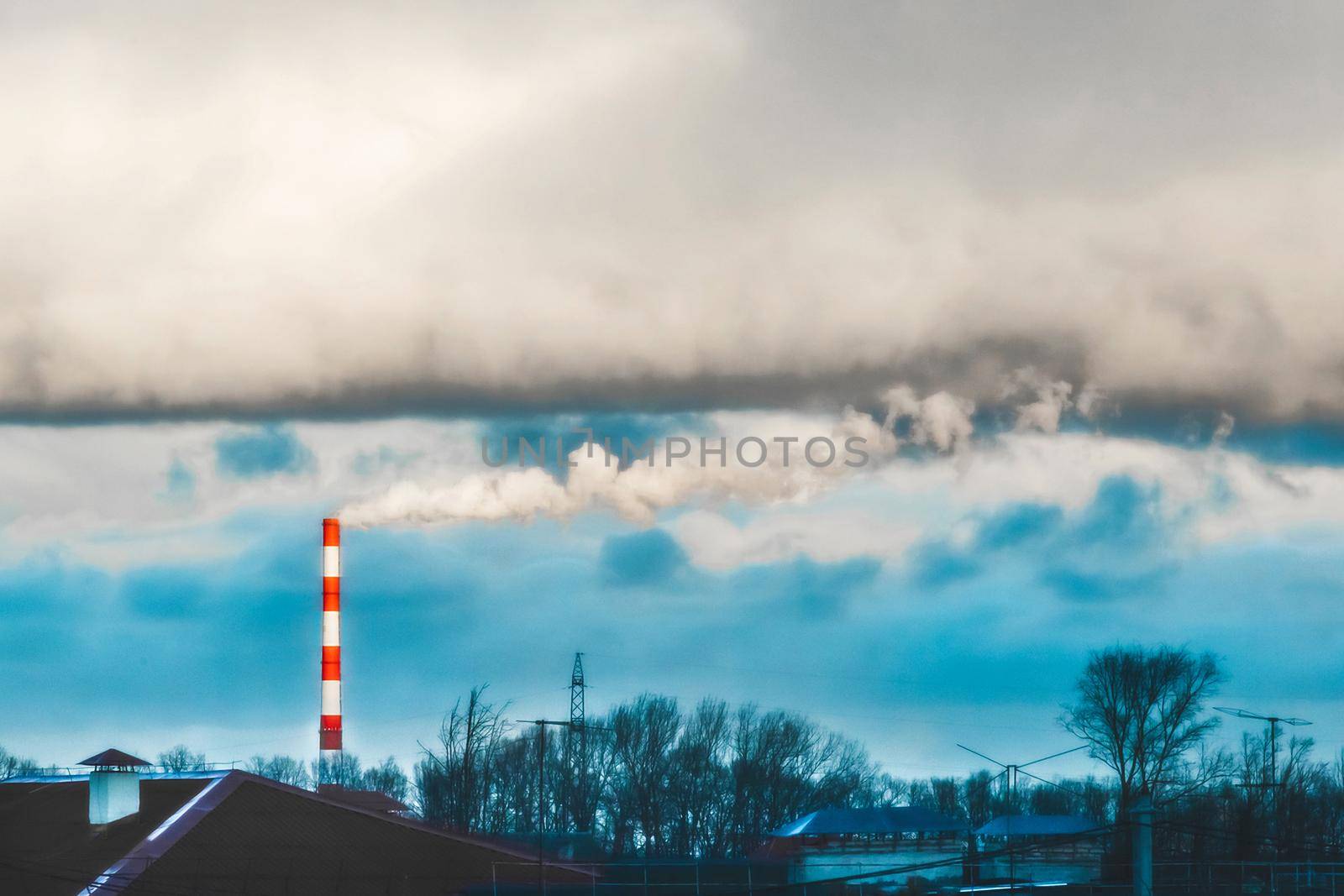 Environmental pollution, environmental problem, smoke from the chimney of an industrial plant or thermal power plant against a cloudy sky.